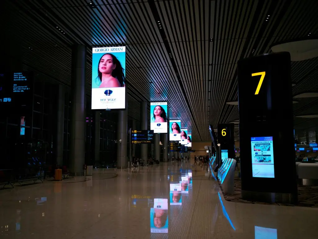pexels-photo-14338583-14338583 Empty airport hallway with digital displays and glossy floors at night.